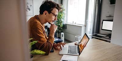 Man achter laptop in zijn huiskamer